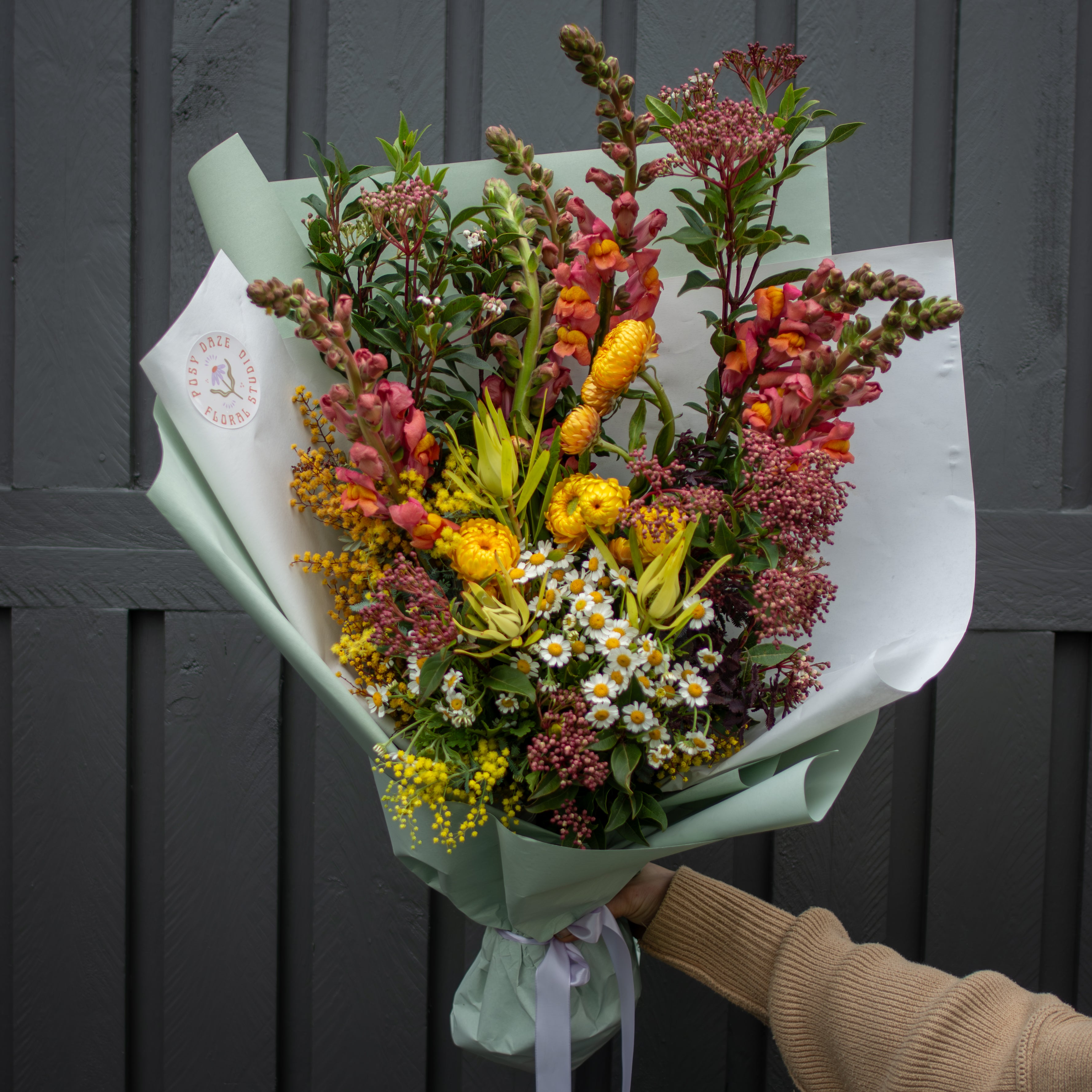 Bouquet of flowers held by a person against a dark wooden background