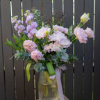 Blush and lavender Mother's Day flower arrangement in ribbed glass vase with satin ribbon, featuring chrysanthemums, hyacinth, lissianthus and stock